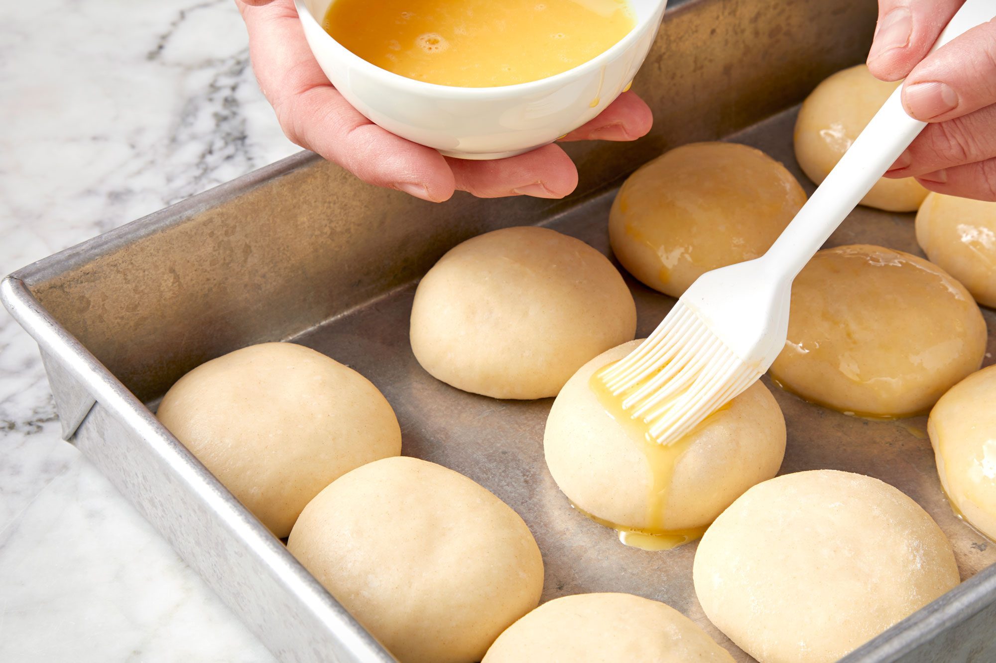 brushing small dough balls; marble surface;