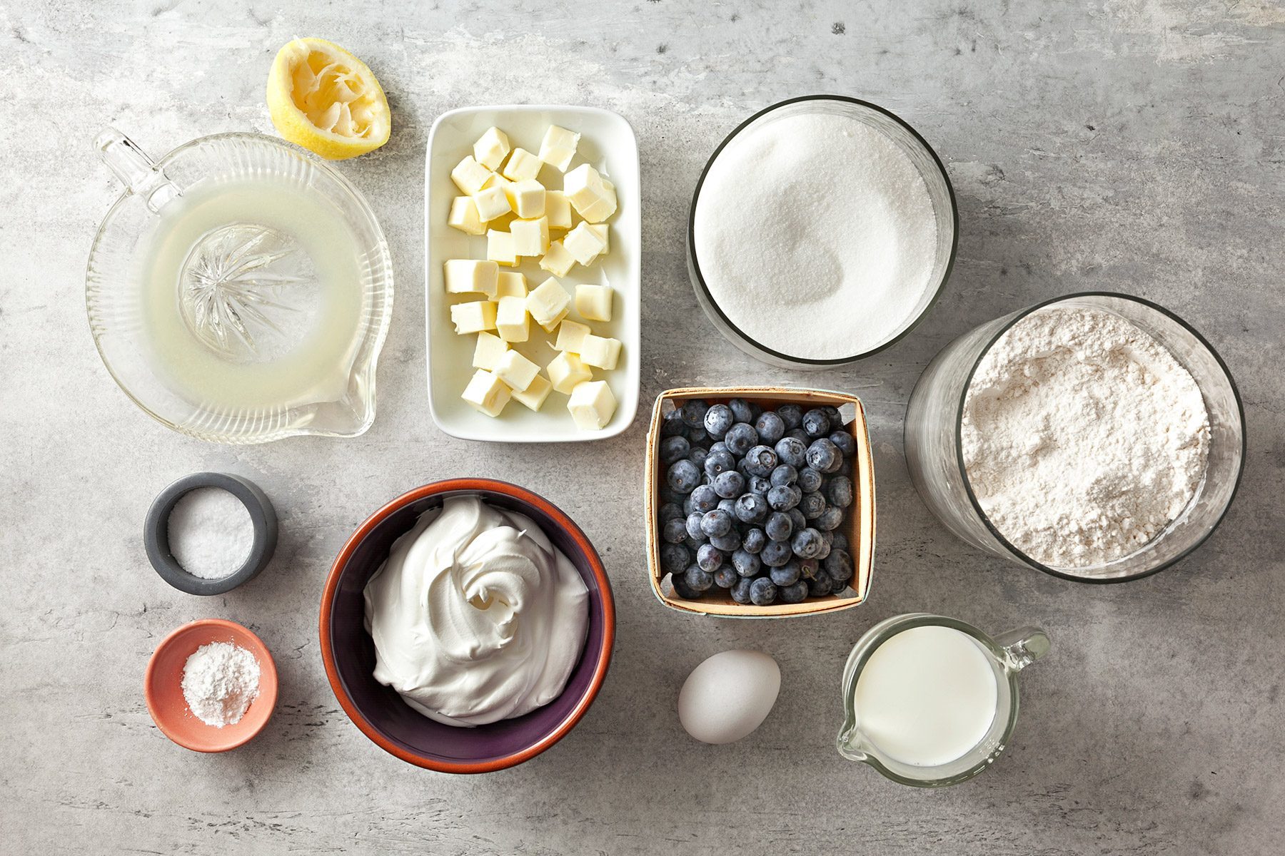overhead shot; grey textured background; Buttery Blueberry Cobbler ingredients placed over background