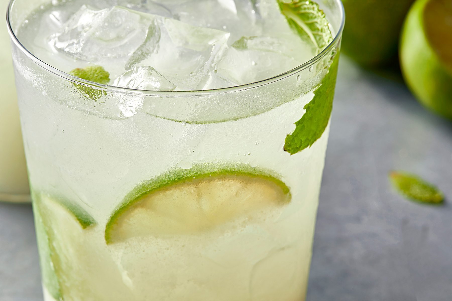 3/4th shot; close shot; grey background; Coconut Mojito served into glasses garnished with additional lime and mint leaves;