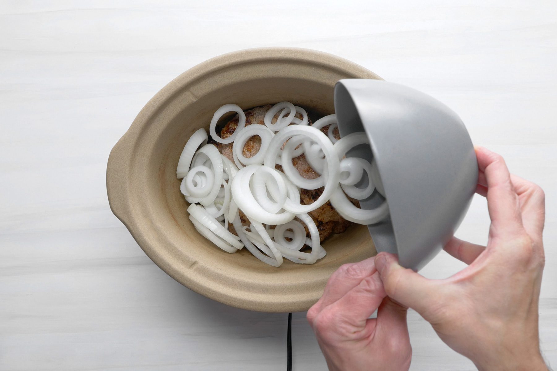A slow cooker with beef cube steaks and onions