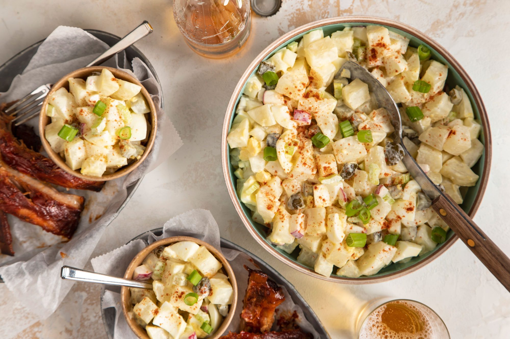 A table with two bowls of Deviled Egg Potato Salad and a glass of beer