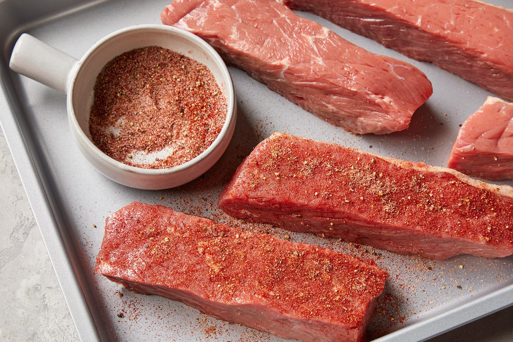 High angle view shot of sprinkle combine mixture over ribs; baking tray; marble background