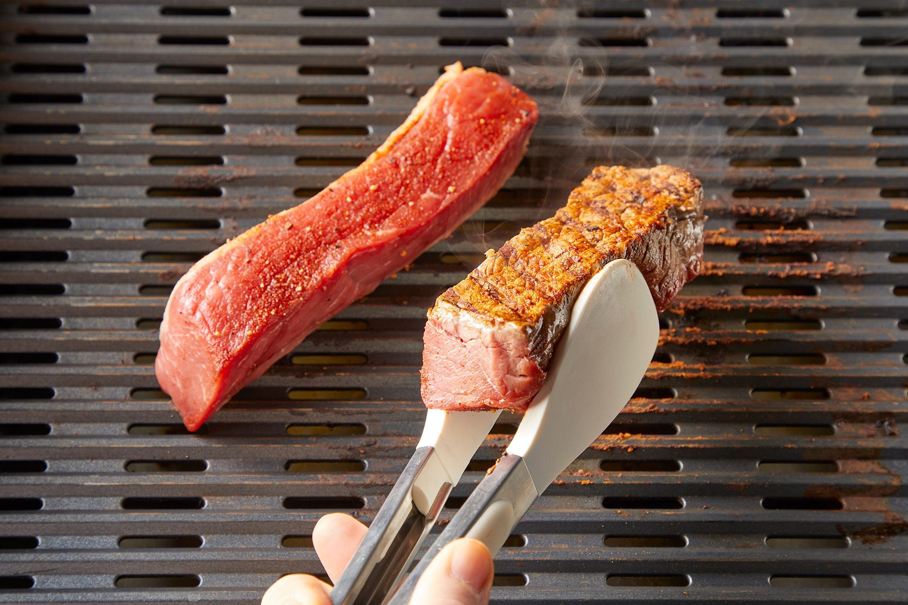 3/4 angle view shot of grill ribs; over medium-high heat; griller; tongs