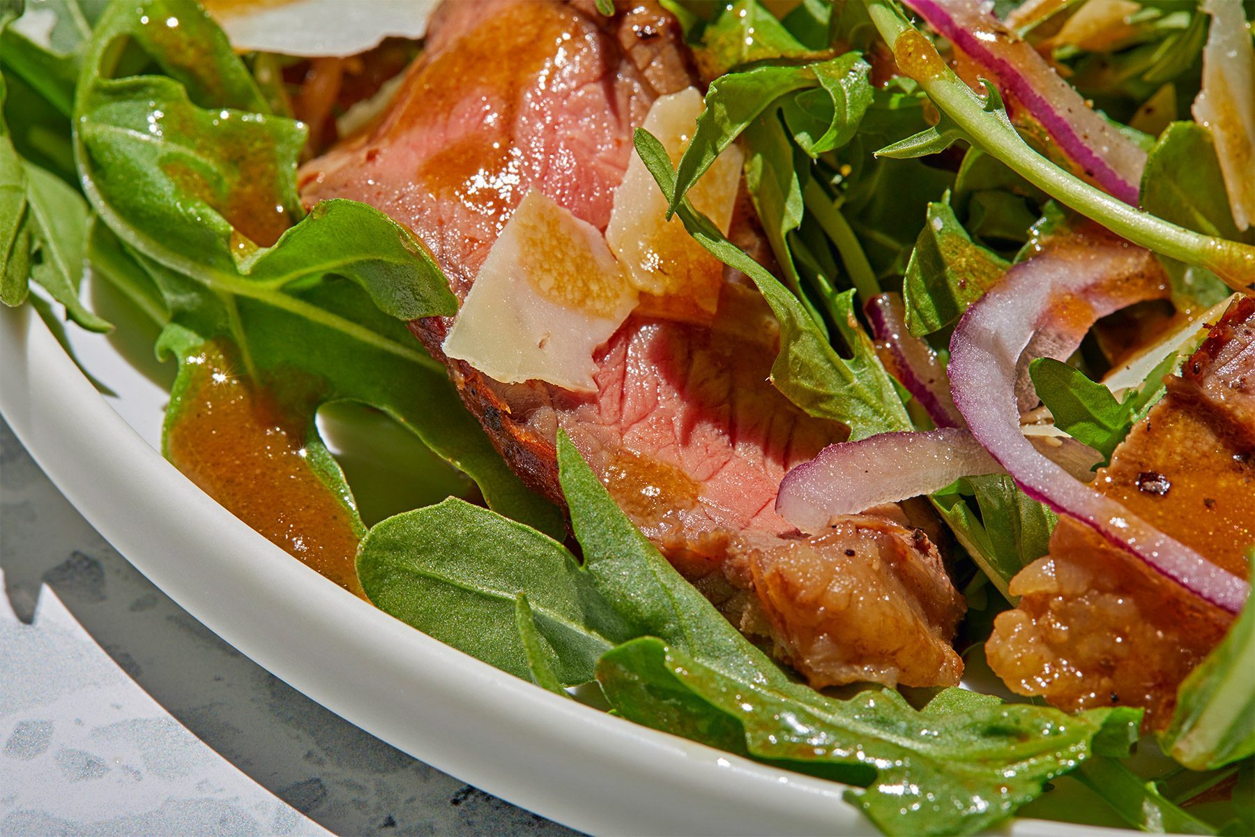 3/4th shot; close shot; white background; Mustard Vinaigrette poured over salad;