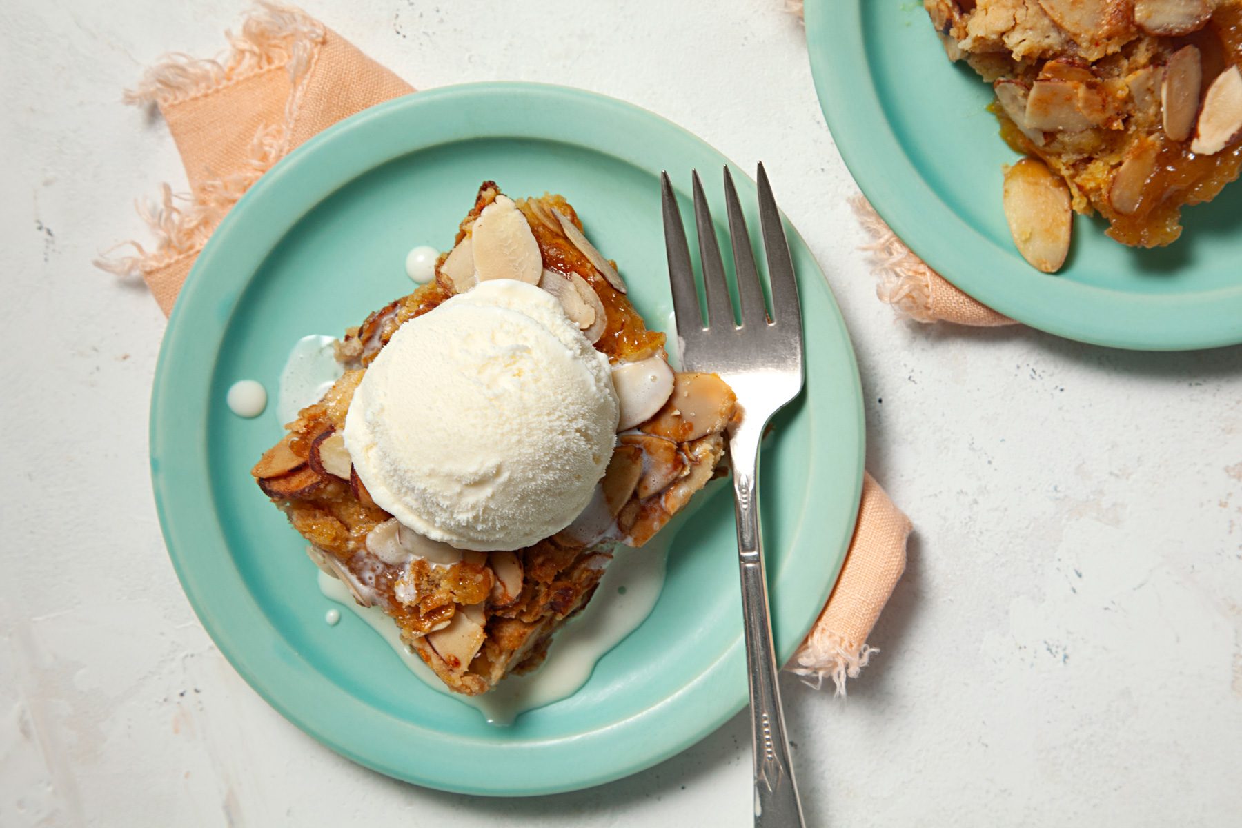 A plate of Peach Cobbler Dump Cake topped with an ice cream scoop, with a fork beside it