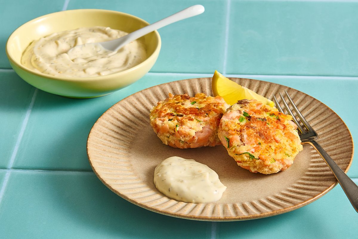 Salmon patties on a plate with some salmon patty sauce and lemon