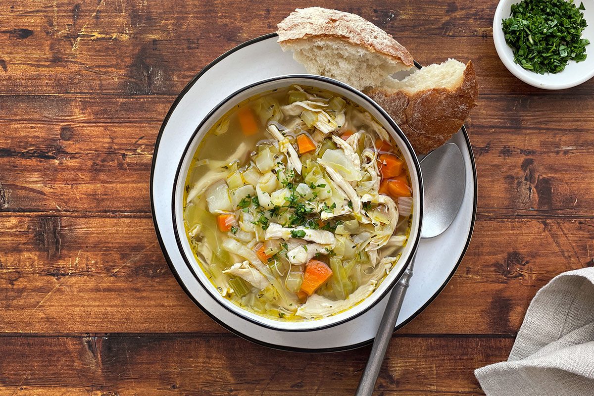 Overhead shot of Taste of Home's Chicken Cabbage Soup on a dark wood background