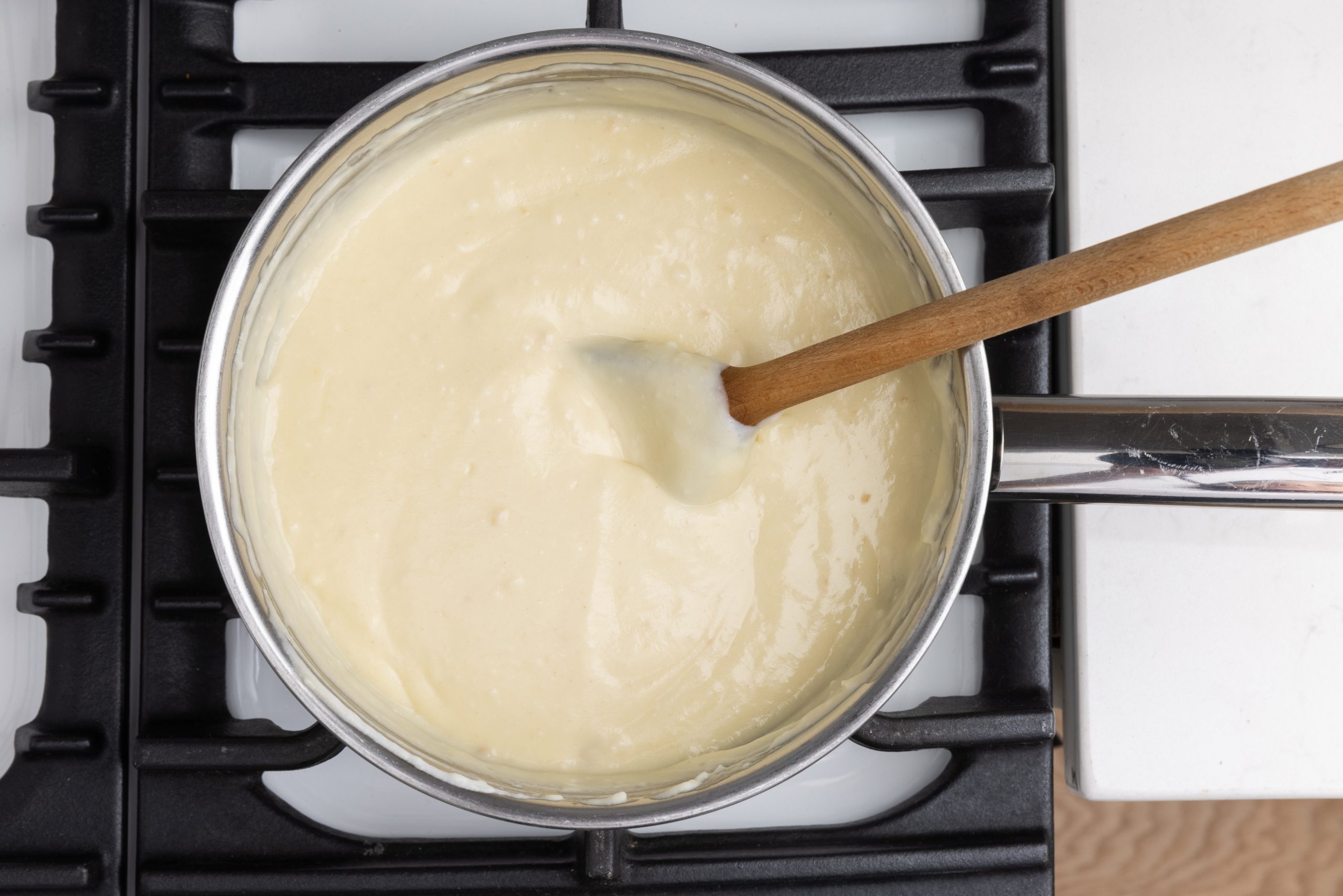 Close up of pot with white sauce being prepared.