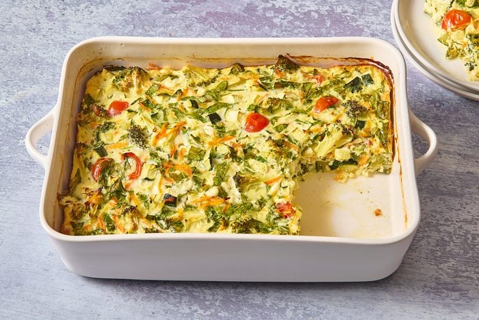 Veggie egg casserole in a baking dish with a slice cut out
