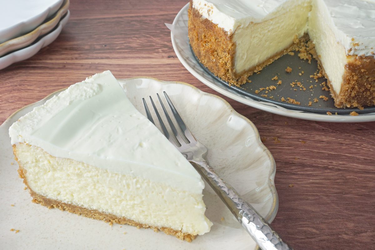 A slice of amaretto cheesecake on a plate near the whole cheesecake RMS 91184 for Taste of Home