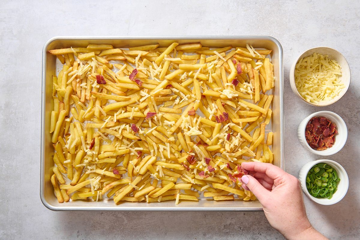 Sprinkling toppings on the cooked French fries