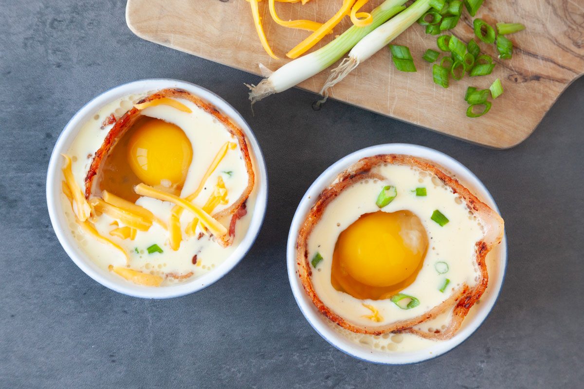 Step 3 of Taste of Home Bacon and Egg Muffins is to line the edges of the ramekins with the bacon strips, then sprinkle half the cheese and onions. Pour in the egg mixture, crack another egg into each one. Top with remaining onions and cheese, bake.