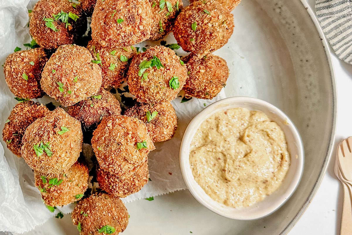 Taste of Home Bitterballen with a bowl of mustard set in a ceramic bowl on a marble surface.