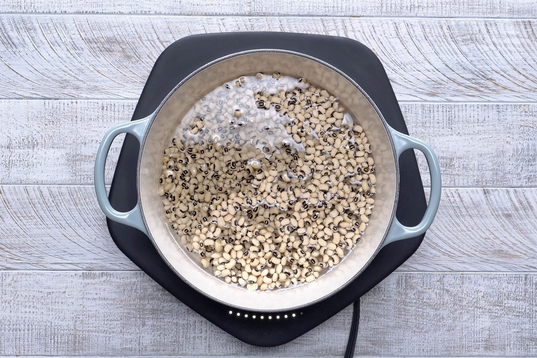 Peas soaked in a dutch oven on a textured background.