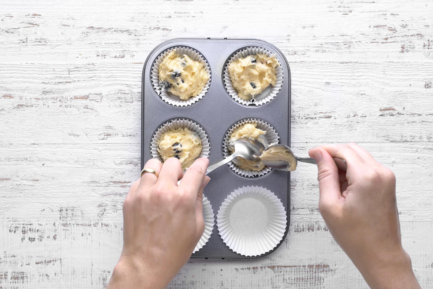 Top view shot of filling muffin baking tray with batter