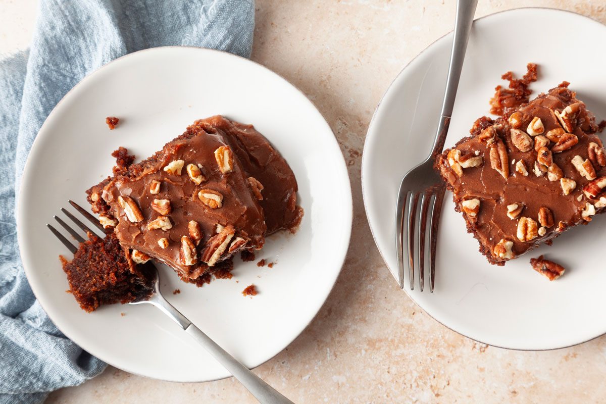 Two single servings of Taste of Home Buttermilk Chocolate Cake on white plates with a light blue linen.