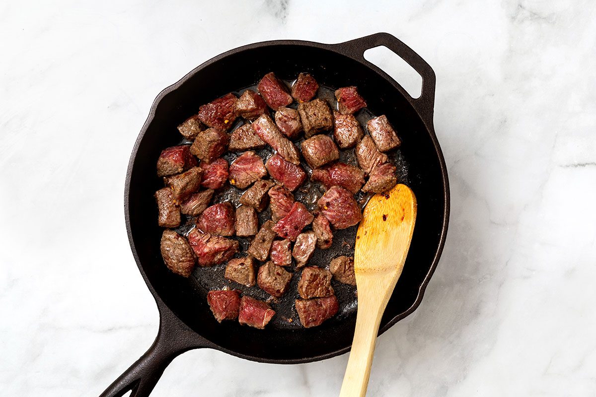 Large skillet of browning cubed steak for step two of Garlic Butter Steak Bites