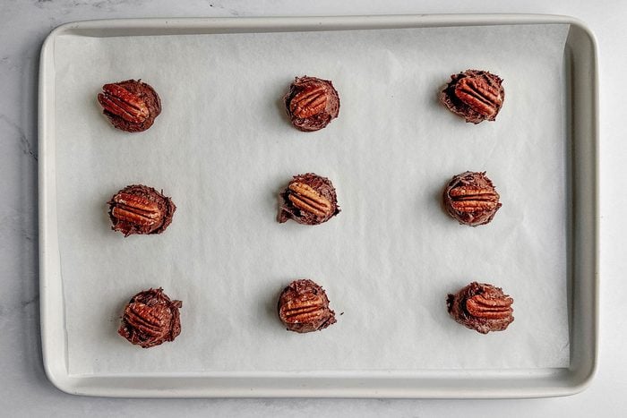 Unbaked Taste of Home German chocolate cookies on a white baking sheet on a marble surface.