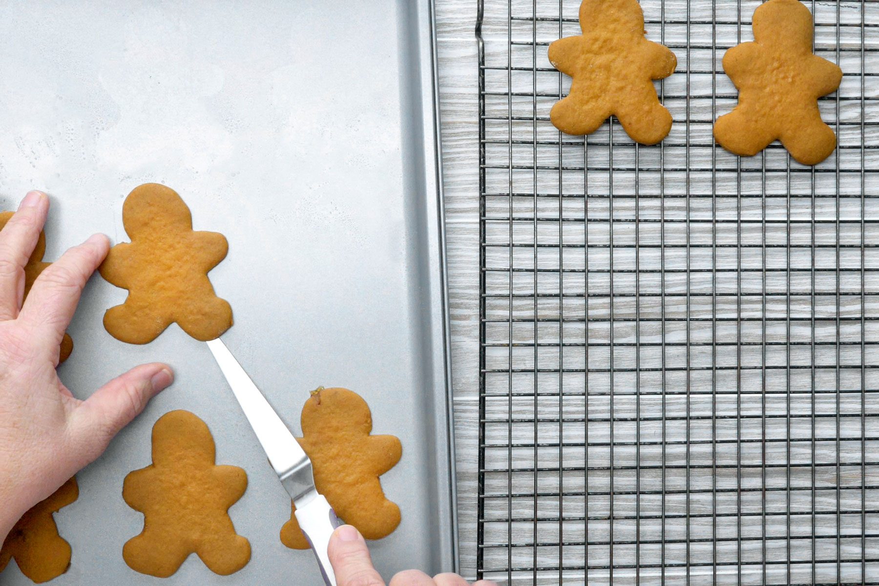 Cookies being moved to wire racks.
