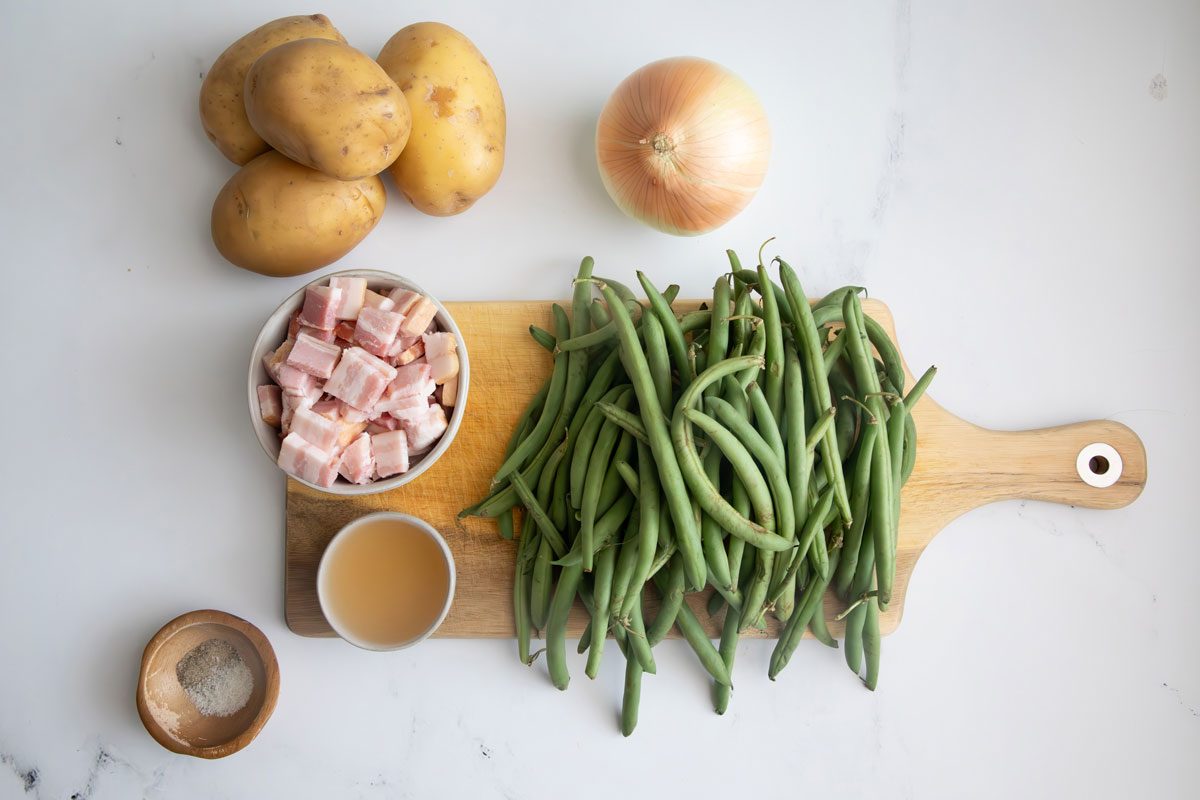 Ingredients for Taste of Home green beans and potatoes on cutting board on a marble surface. 