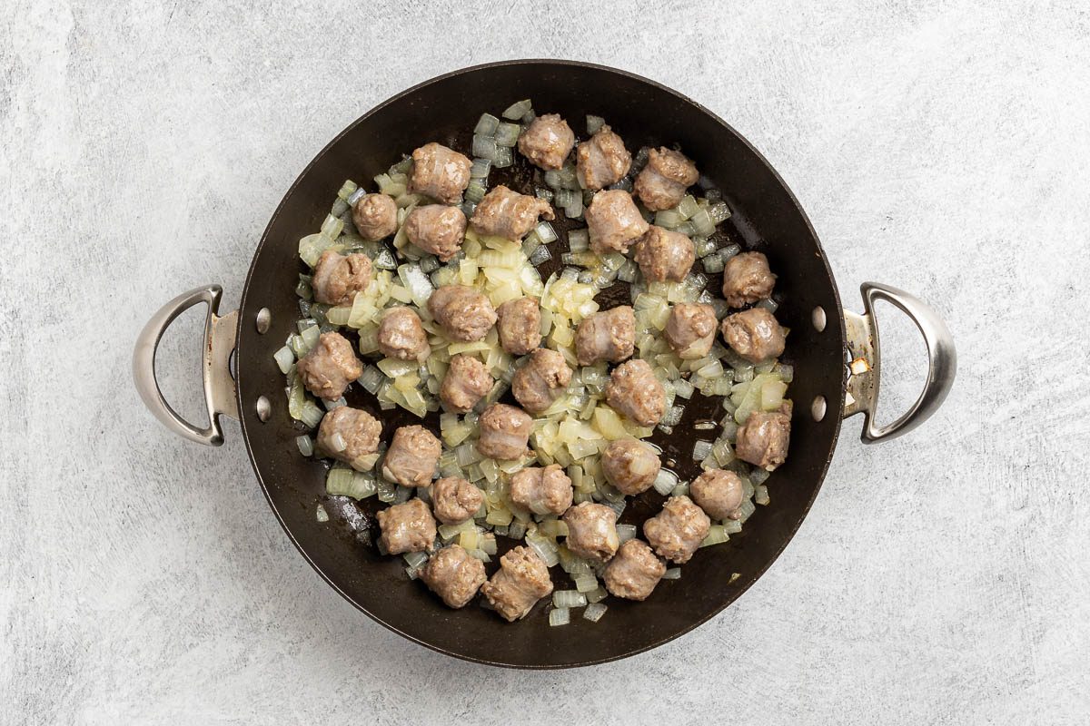 Taste of Home Sauerkraut Casserole recipe photo of the cooked sausage and onion in a large skillet.