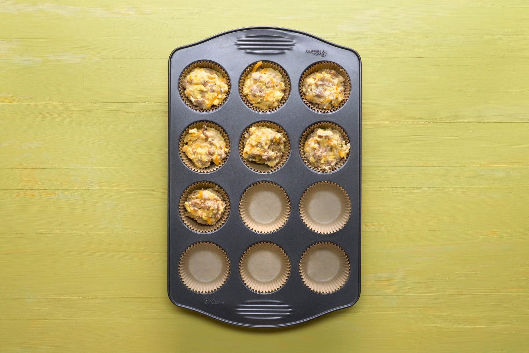 Top view shot of muffin cups three-fourths full with the muffin batter in baking tray