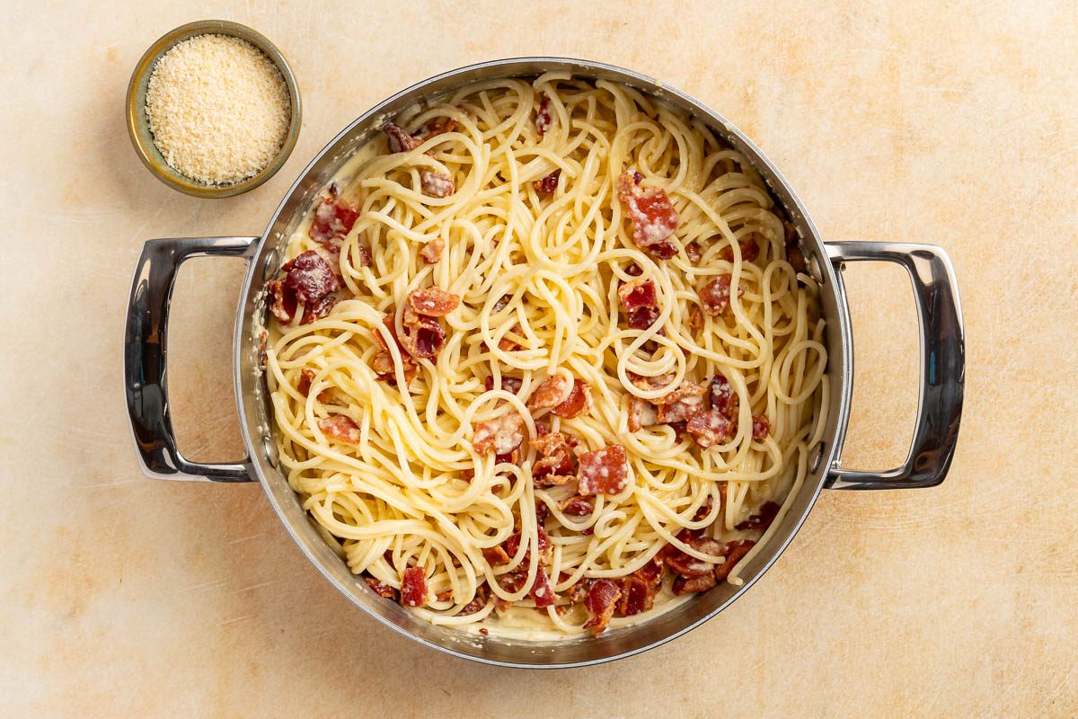 Taste of Home Skillet Pasta with Bacon and Egg recipe photo of combining the sauce and the pasta together in the skillet.