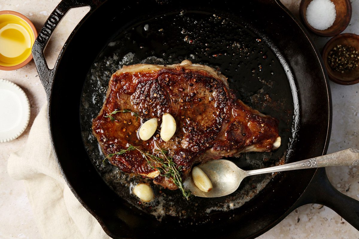A how to look into Taste of Home's homemade Steak Frites. Steak in a cast iron pan with butter, garlic and thyme.