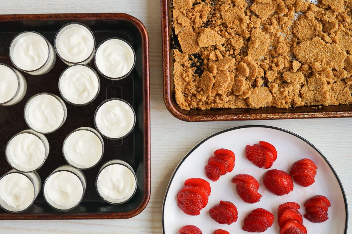 Cheesecake Mousse in jars ready to be topped with graham cracker and strawberry toppings 