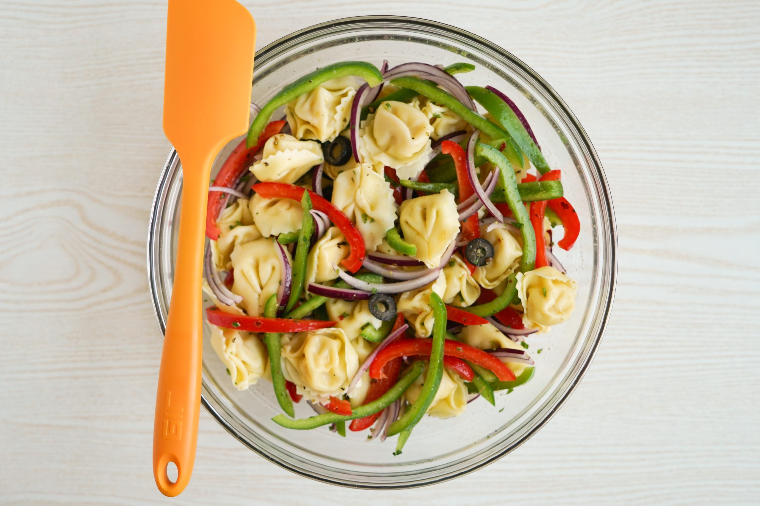 Mixing together tortellini pasta salad
