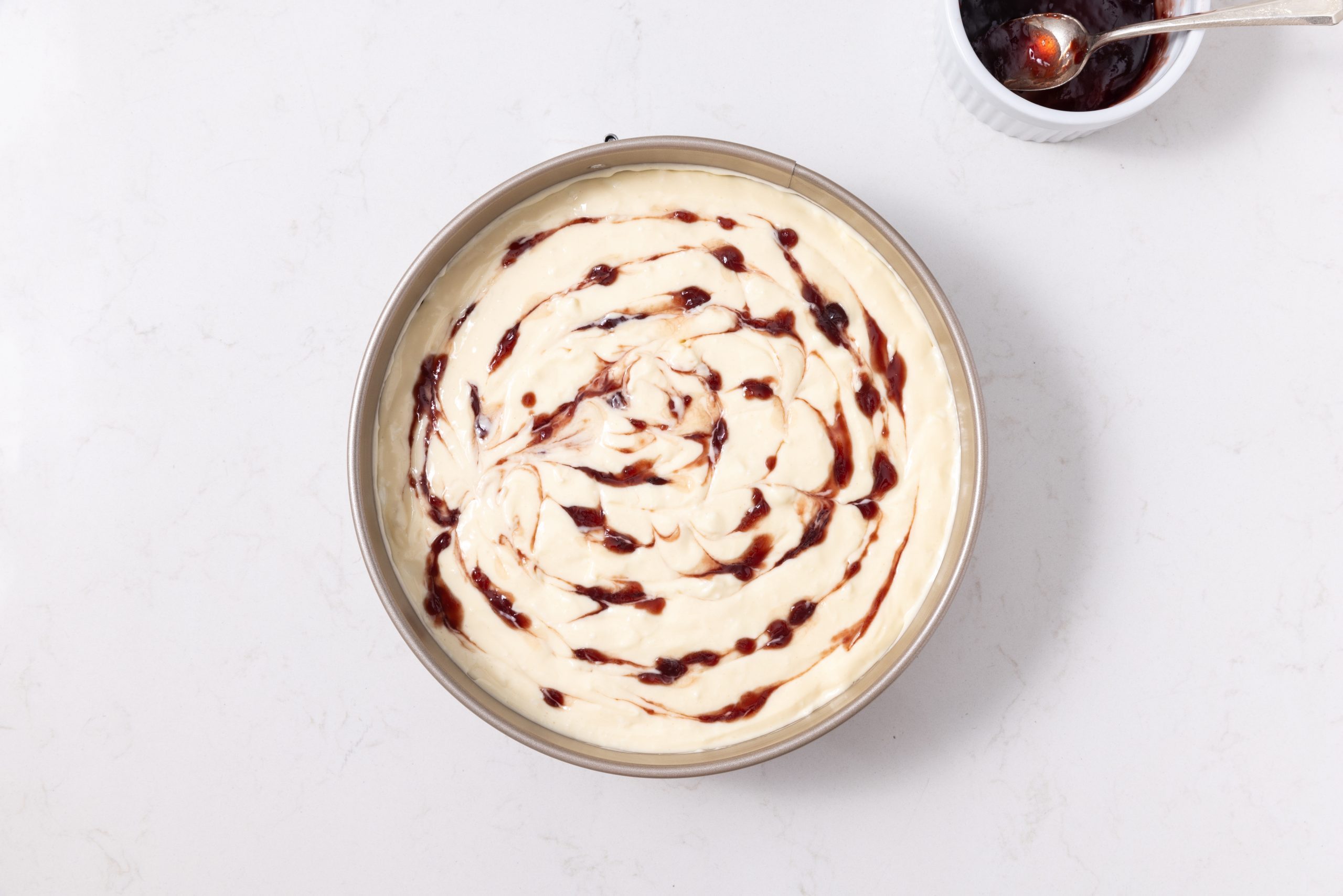 Cheesecake in springform pan with raspberry jam swirl.