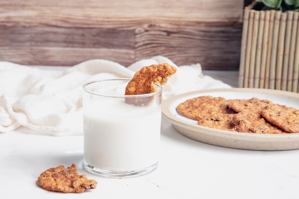 Horizontal beauty shot for Taste of Home Apple Butter Cookies with cookie being dipped in to milk on a marble surface.