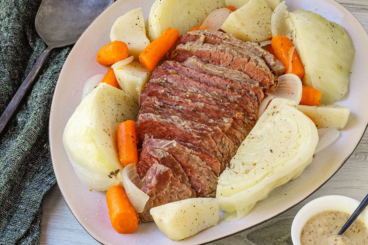Closeup photo of boiled dinner on a platter with corned beef and cabbage, from Taste of Home.