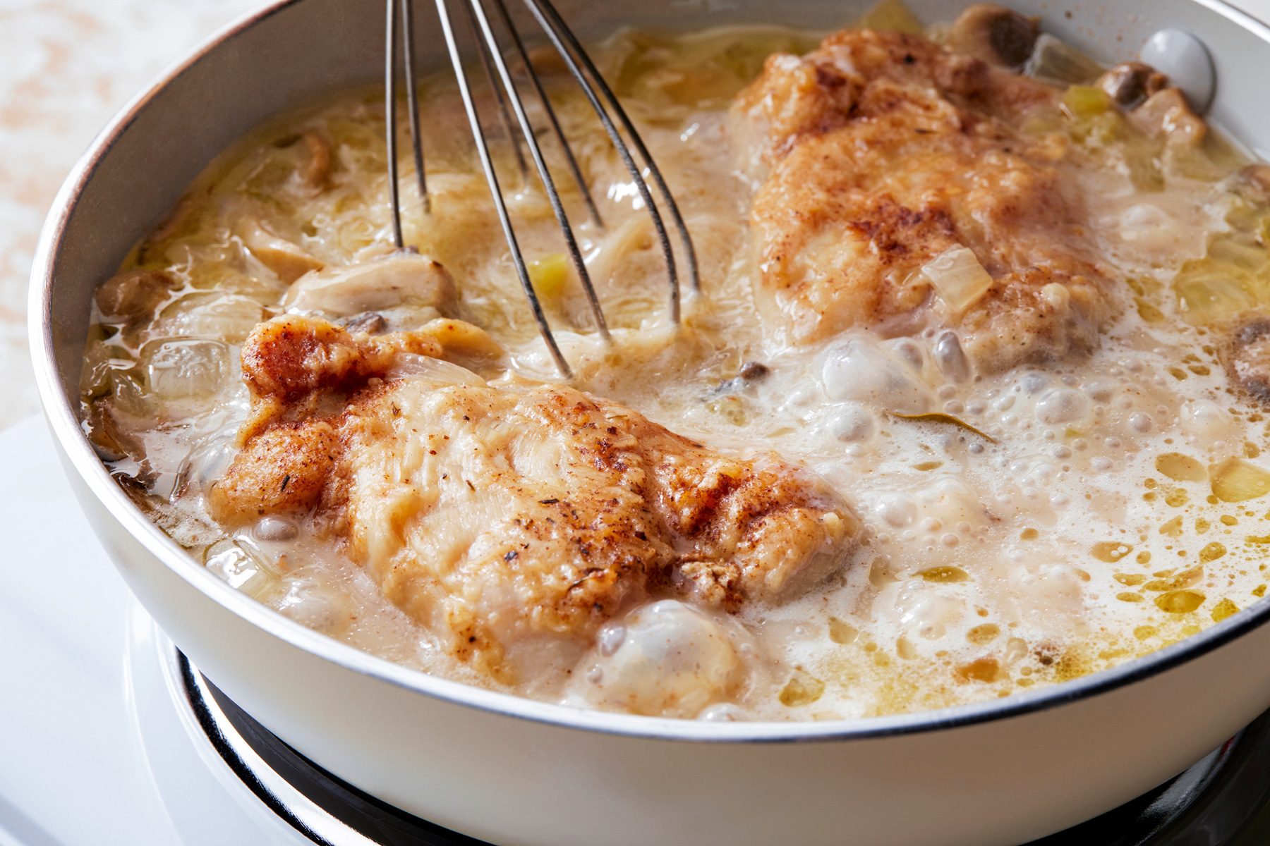 3/4th shot; white textured background; Heating and constantly stiring mixture until it thickens