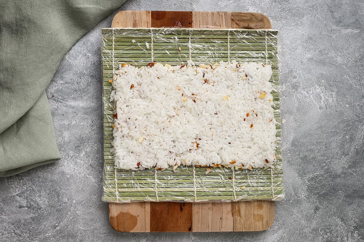 Chicken tempura roll preparation showing the rice on a sushi mat.