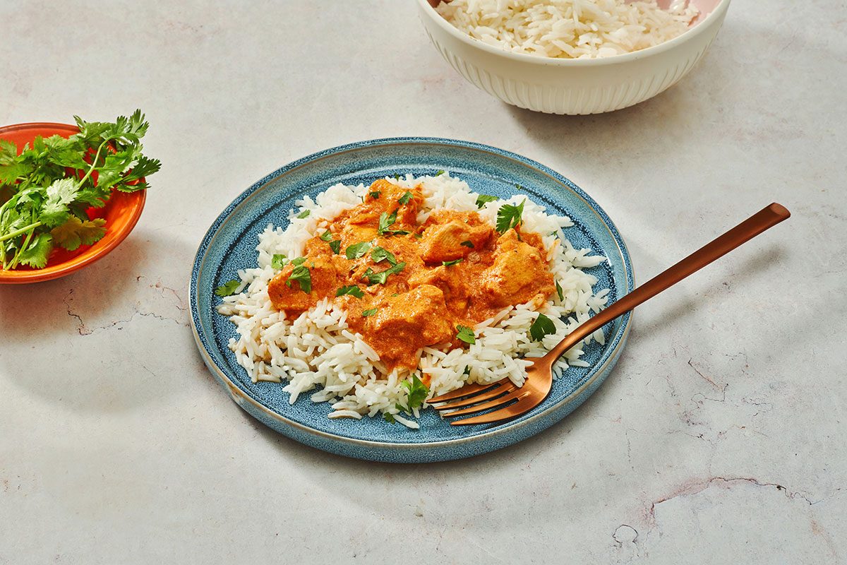 Chicken tikka masala served over basmati rice garnished with chopped cilantro