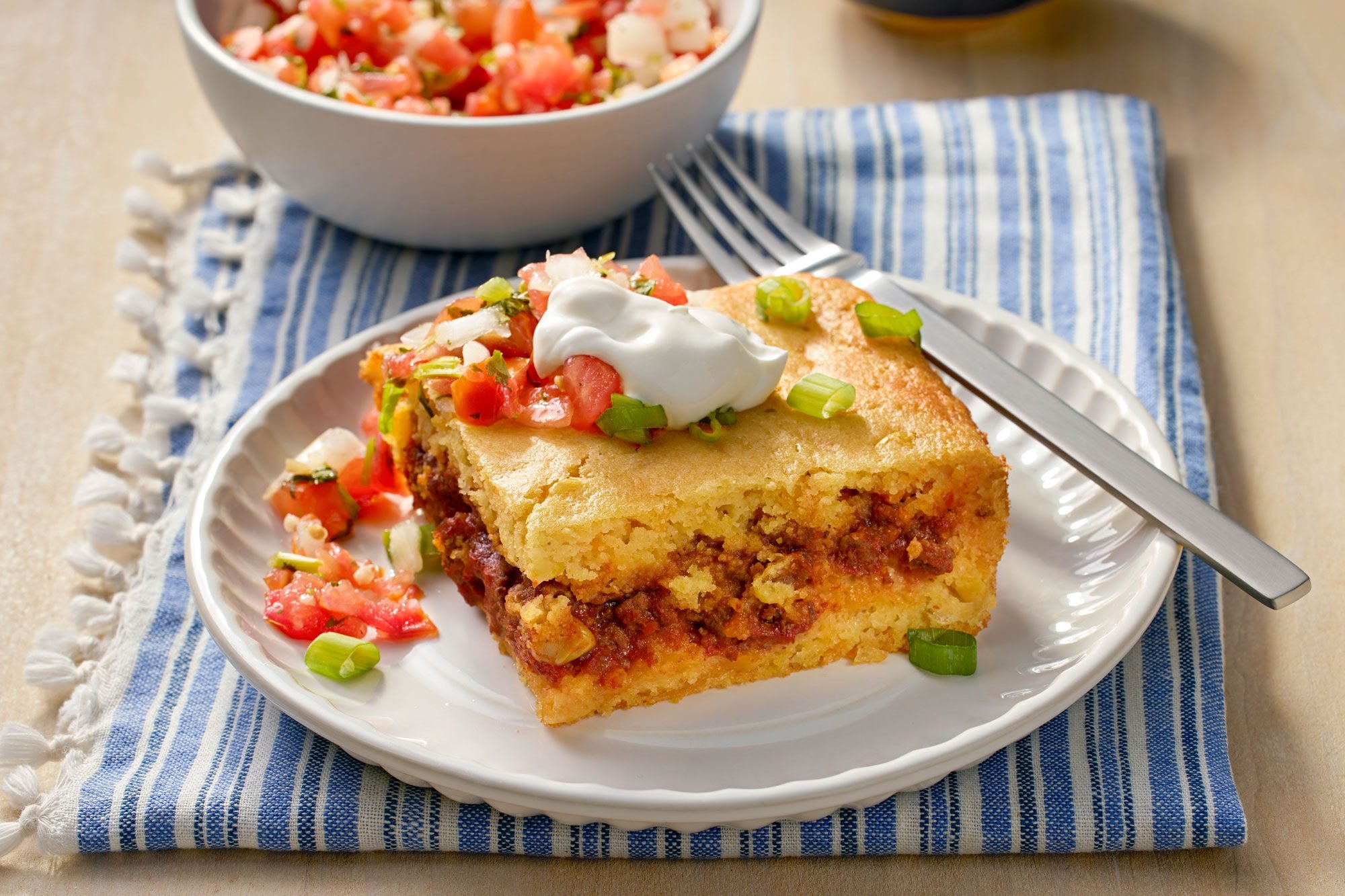 3/4th angle shot of chili cornbread casserole served with sour cream and salsa