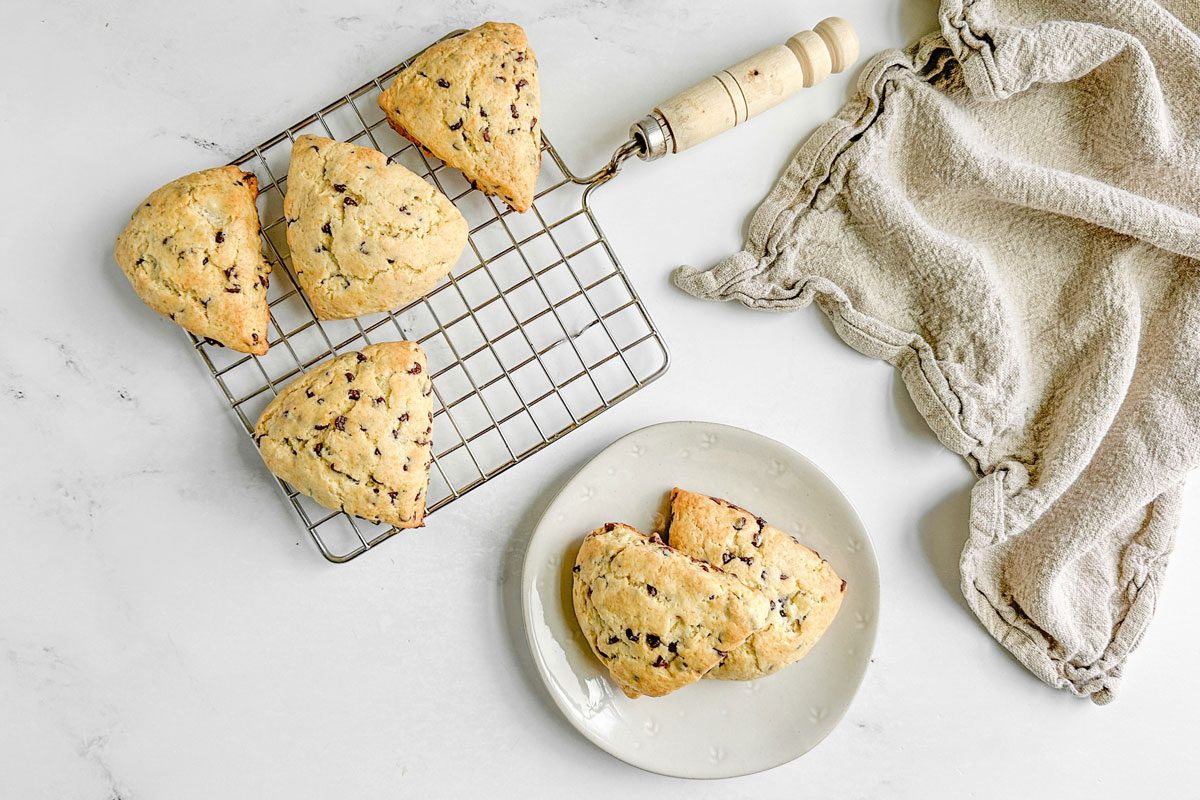 Taste of Home Chocolate Chip Scones on a white plate and a wire rack on a marble surface