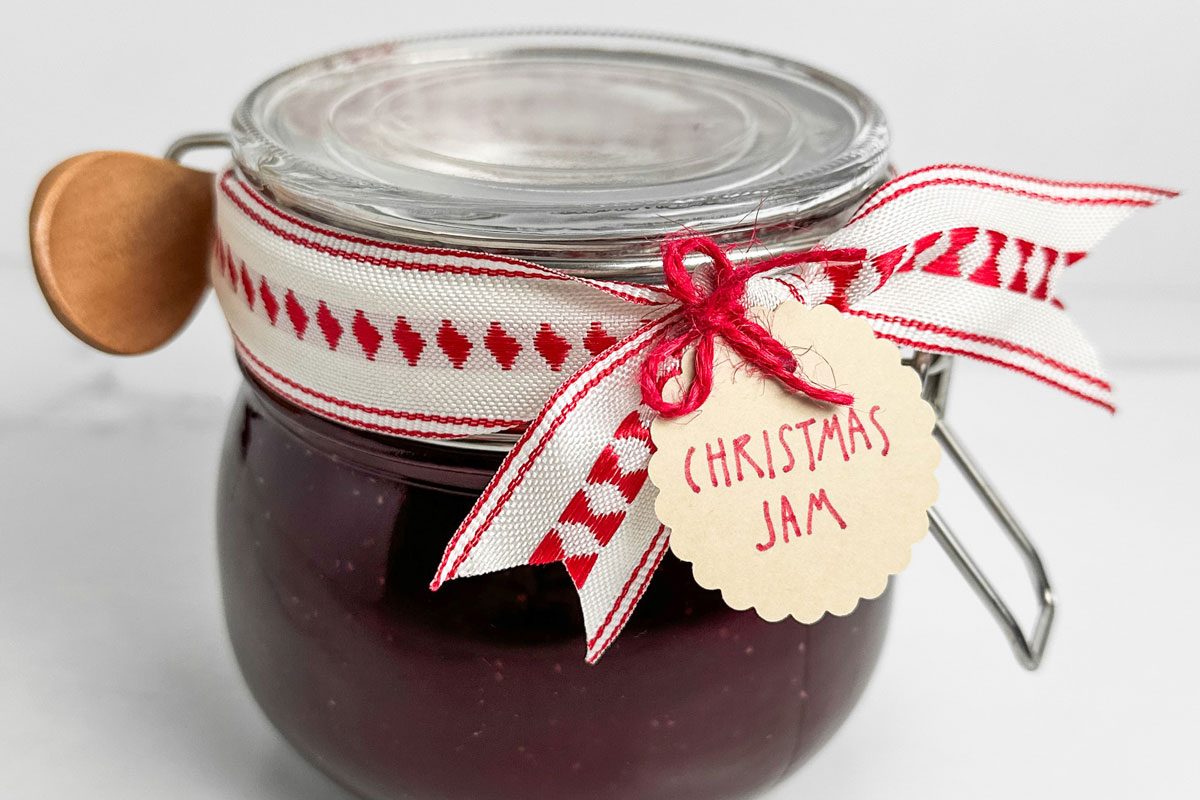 Taste of Home Christmas Jam in a ribboned mason jar with wooden spoon
