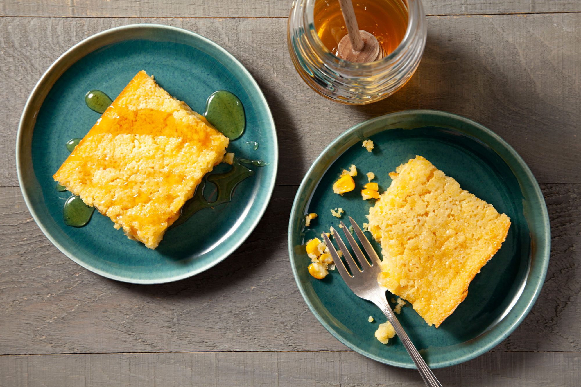 Corn Pudding cut into pieces and served in plates dressed with honey on top