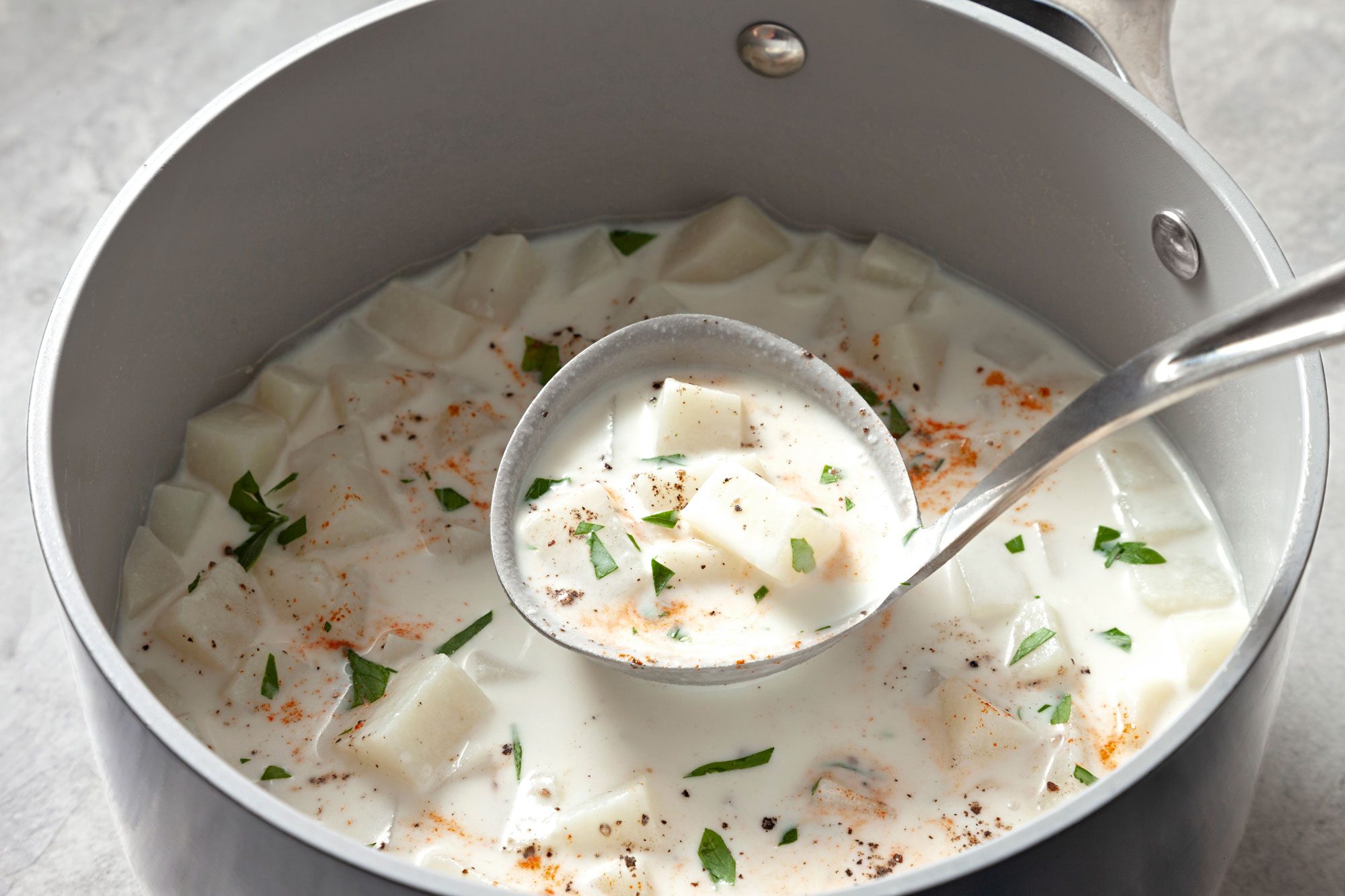 Cream of Potato Soup in a large saucepan; close view of Cream of Potato Soup in serving spoon