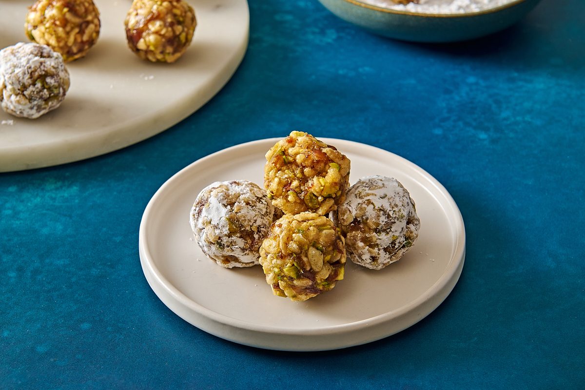 Closeup shot of a few date nut balls served on a plate, with a bite taken out of one 