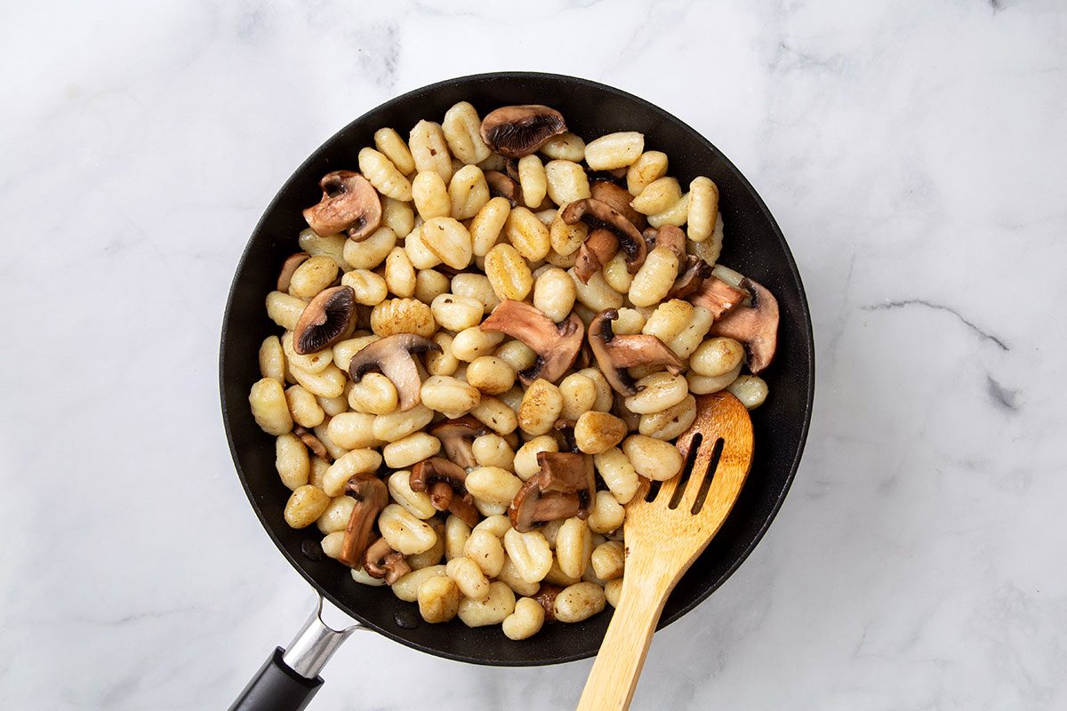 Cooked mushrooms and gnocchi with melted better in a large skillet for Gnocchi Alfredo recipe for Taste of Home