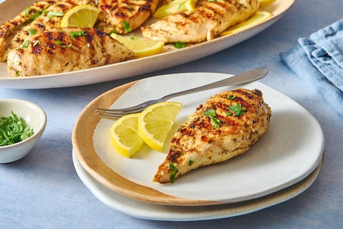 Closeup shot of grilled lemon chicken served on a plate with some lemon slices