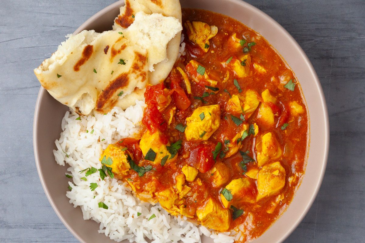 Single serving of Taste of Home Instant Pot Chicken Curry served with rice and naan, garnished with cilantro
