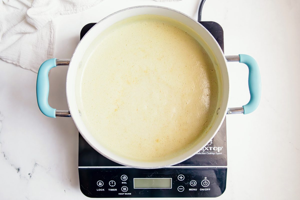 Overhead shot for Taste of Home Jalapeno Jelly with jelly in a large pot on an induction stovetop.