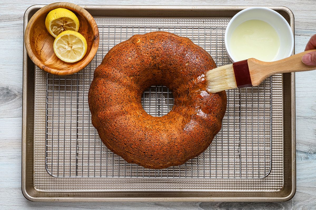 Brushing the lemon poppy seed cake with lemon glaze.