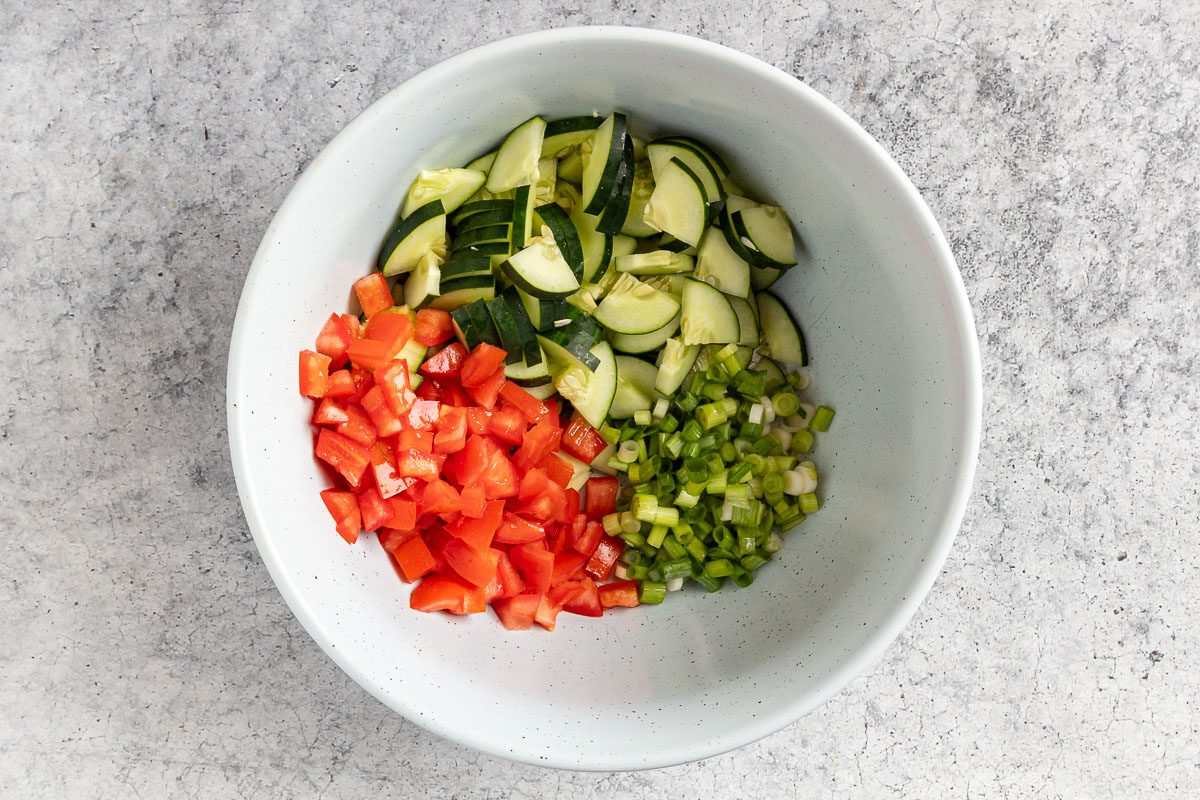Taste of Home Linguine Salad recipe photo of the tomatoes, cucumber and the green onions in a mixing bowl.
