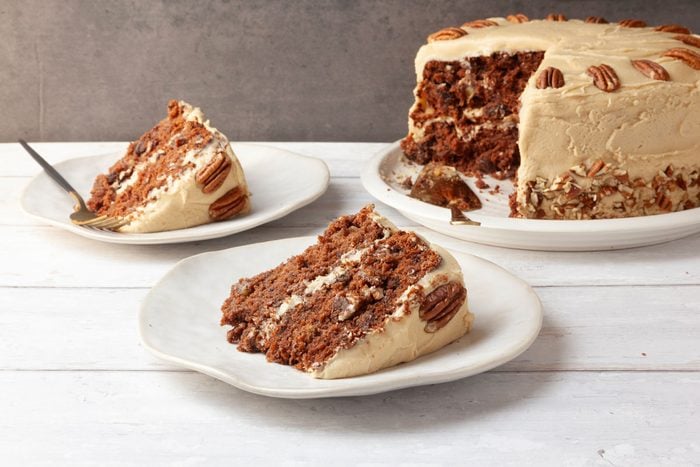 Full yield of Taste of Home Jam Cake on white wood surface with single servings, gold pie cake server