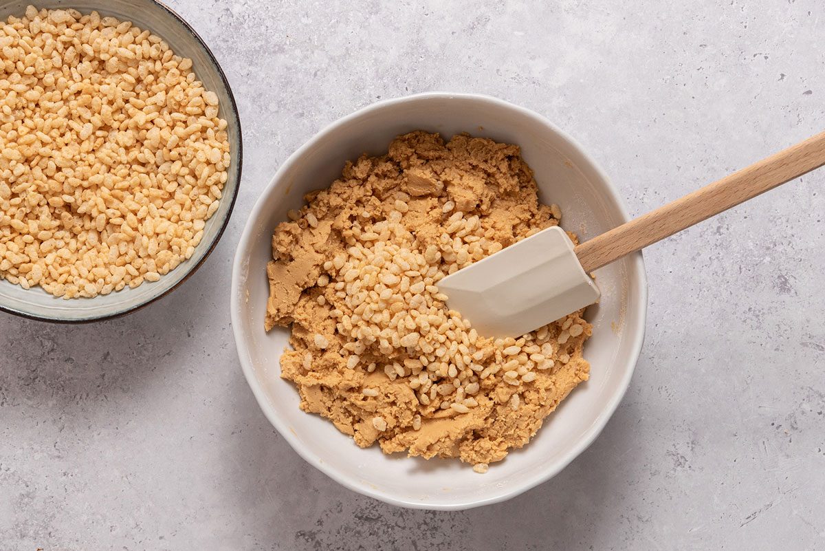 Mixing rice crispies to peanut butter mix
